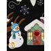 A close up shot of an appliqué snowman wearing a blue hat and scarf next to a teal house with a pink heart door.  