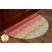 A half-oval area rug with a colorful pattern of stripes in shades of red, orange, and green, placed against a wooden cabinet on a wooden floor.