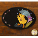 A whimsical design on a black circular mat featuring a yellow duck holding a blue umbrella while splashing in a puddle, surrounded by colorful flowers and raindrops.