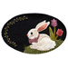 An oval rug featuring a cute white rabbit with a purple bow sitting on grass, surrounded by decorative flowers and green leaves against a black background.