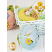 A decorative arrangement of colorful felt Easter eggs, featuring various floral designs and shapes, sits in a white woven basket. The eggs have embellishments such as a white bunny and flowers, alongside a yellow egg with a chick design.