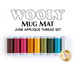 A collection of colorful thread spools arranged in a row, featuring shades of brown, pink, orange, yellow, green, blue, and white. Above the spools, the text reads WOOLY MUG MAT and JUNE APPLIQUE THREAD SET.