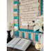 Cream, beige, and aqua colored quilt featuring a script of the Amazing Grace on a wall by a candle, with an open Bible on a table next to white flowers.