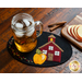 Small black wool mat with a school house and yellow apple stitched down, topped with a glass of tea