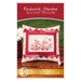 The front of the Redwork Garden Accent Pillow Pattern, showing the finished redwork pillow displayed on a wooden table with flowers peeking from the side of the frame.