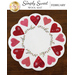 A circular wool mat featuring a design of 12 decorative hearts in various shades of red and pink, arranged around a floral motif. The mat has a soft white background and is labeled Simply Sweet Wool Mat February.