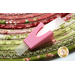 A close up of the pink Jellyroll Jig on top of a floral red and green jelly roll rug.