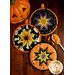 Three different Halloween hot pads displayed on a wood table