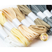 A selection of elastic cord spools in various colors, including white, yellow, beige, gray, and black, stacked together with white labels around the center of each spool.