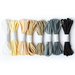 A collection of eight bundles of elastic cords in various colors arranged horizontally. The colors include white, pale yellow, light tan, beige, olive, light gray, dark gray, and black. Each bundle is secured with a white label.