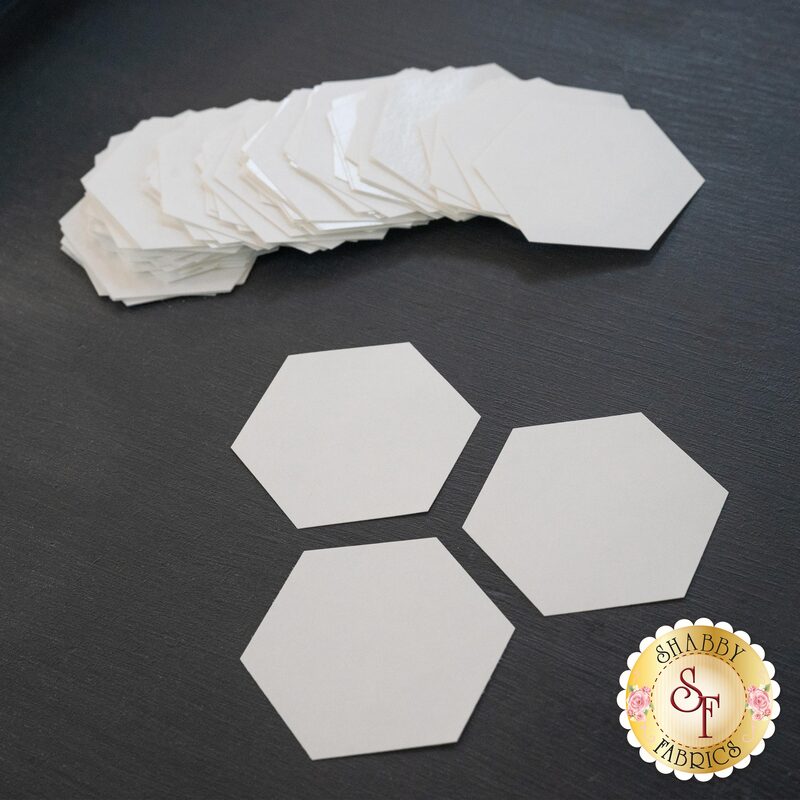 A stack of white hexagonal paper pieces with three individual hexagons placed in front on a dark background.