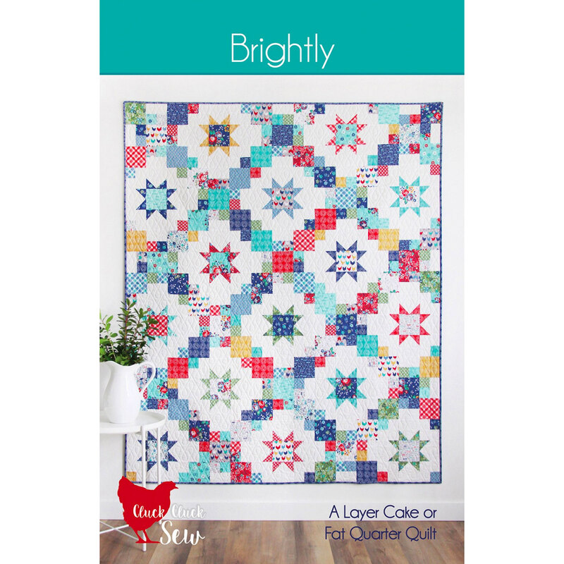 Brightly colored quilt by Cluck Cluck Sew displayed on a wall, featuring star patterns on a white background.