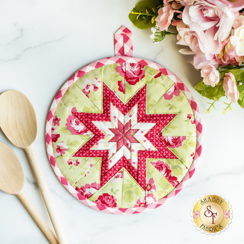 Green floral circular hot pad on a brown wood table