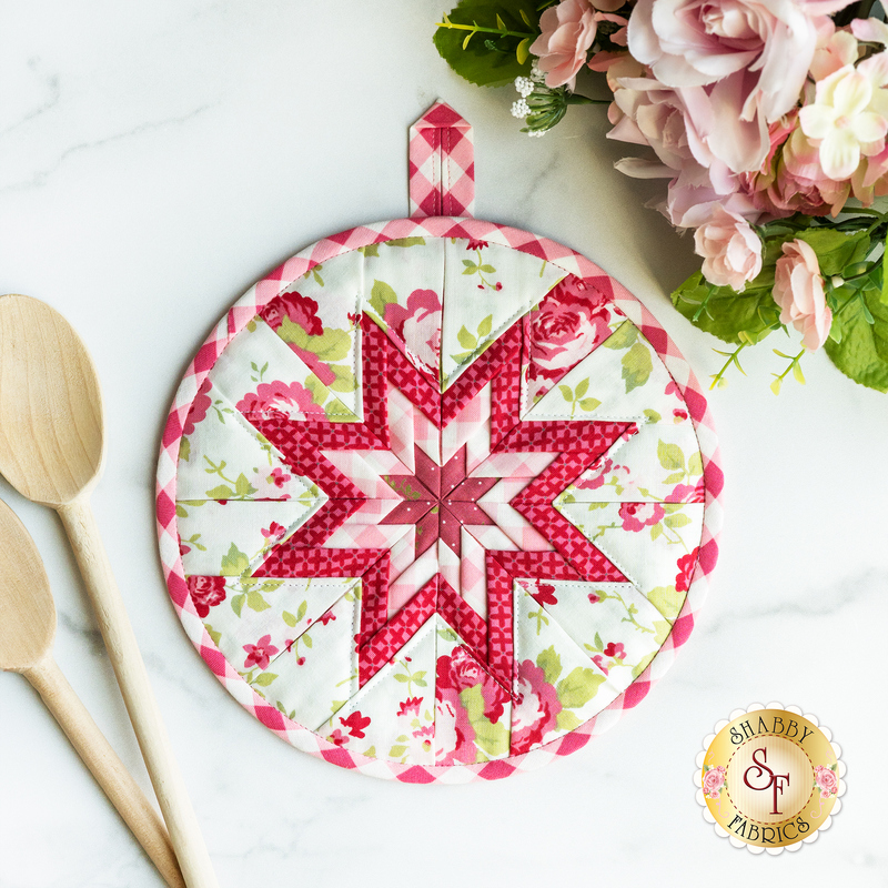 White and red floral circular hot pad on a wood table