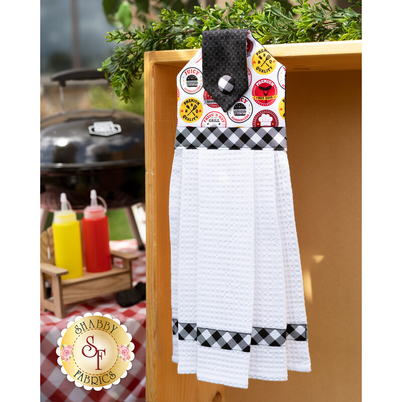 White hanging towel hung outside in front of a picnic table and bbq