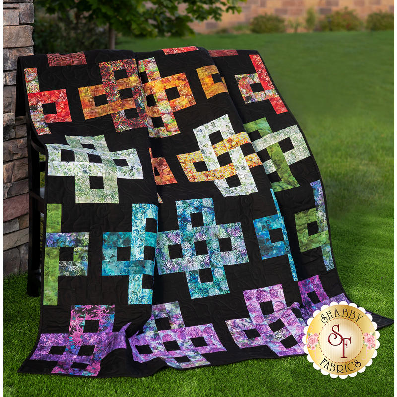 A colorful quilt featuring intricate patterns of interconnected shapes on a black background.