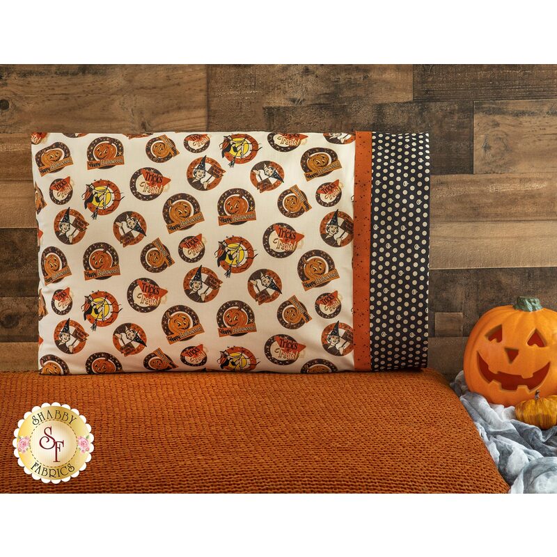 Halloween themed cream pillowcase featuring witches, jack-o-lanterns, and phrases with black banding featuring cream polka dots.