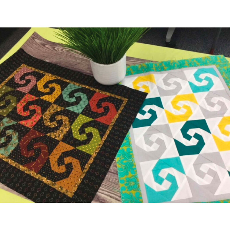 Two colorful Simply Snails Mini Quilts laid flat on a wood table