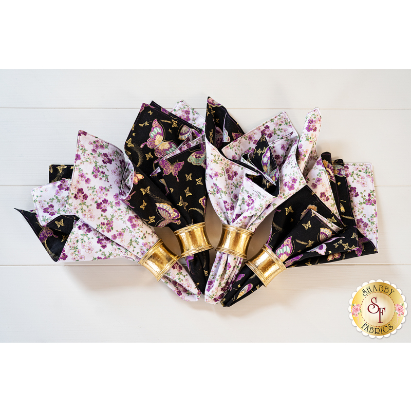 Reversible cloth napkins one side features black fabric with purple butterflies, the other side features white fabric with purple florals.