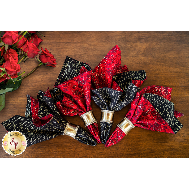 Reversible cloth napkins featuring packed red roses on one side and white cursive writing on black on the other.