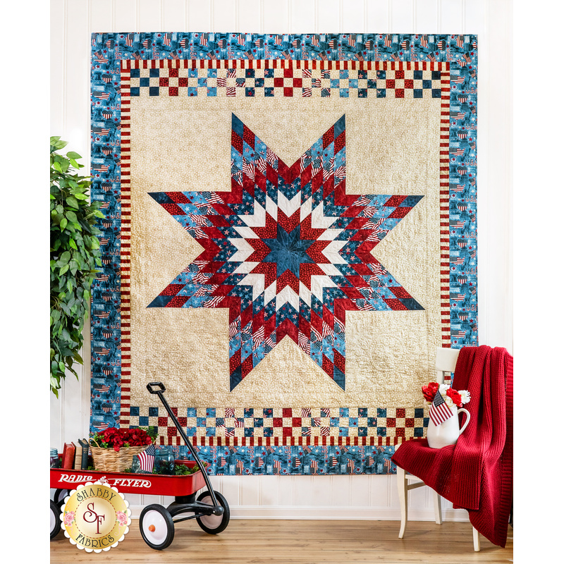 Quilt with giant starburst design made of patriotic red, white, and blue fabrics on cream background.