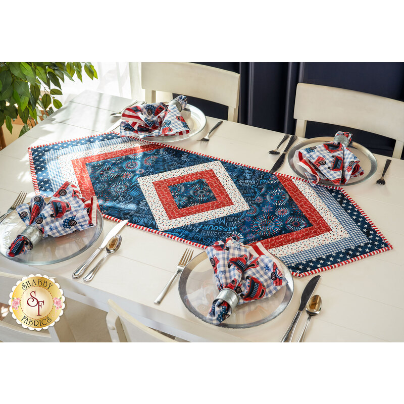 Table runner with central diamond design and angled strips at the ends made of patriotic printed fabrics.