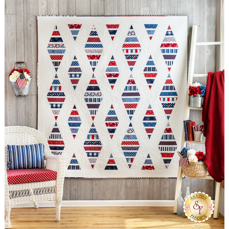 White quilt with diamonds made of strips of red white and blue patriotic fabrics.