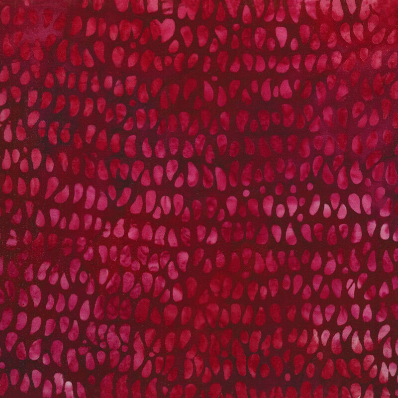 Tonal mottled fabric of red and pink teardrop dots on a burgundy background.