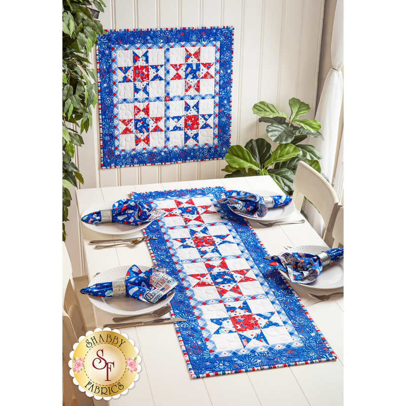Geometric wall hanging and table runner made of patriotic summer themed fabrics in red, white, and blue.