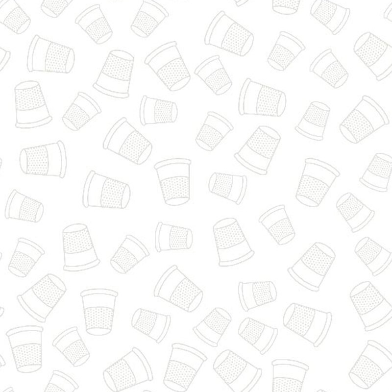 light grey thimbles tossed on a white fabric background.
