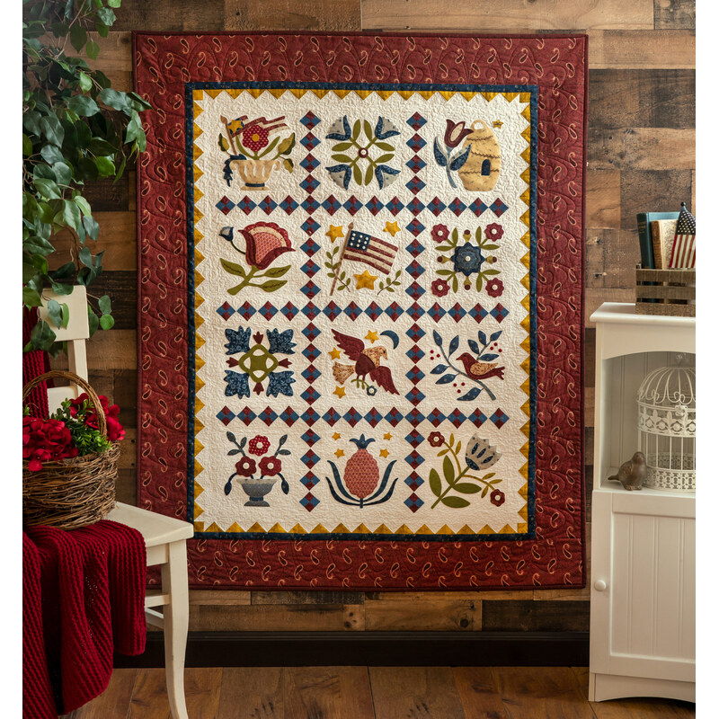 A colorful quilt features floral and bird patterns set against a red and white backdrop.