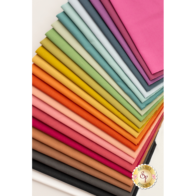 A stack of folded fabric swatches in various colors, arranged in a gradient from pinks and oranges at the bottom to greens and blues at the top.