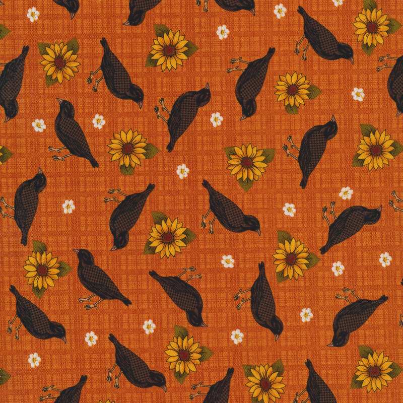 Sewing fabric with small flowers, black birds, and sunflowers all over an orange background