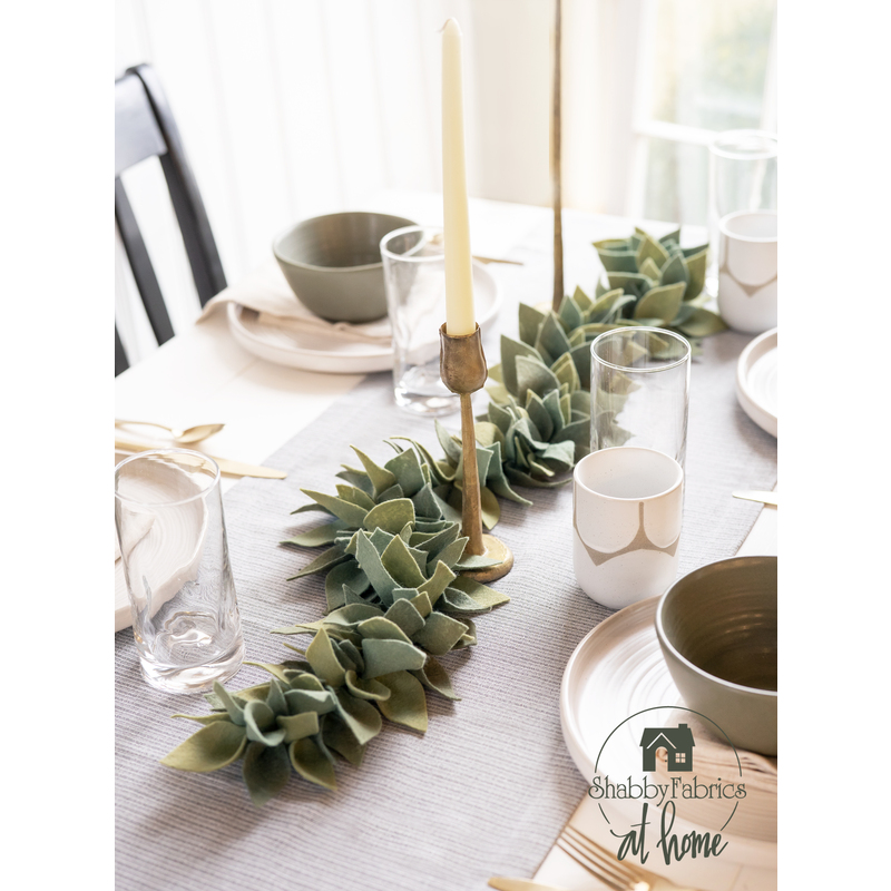 A sage leaf felt centerpiece set on a modern table