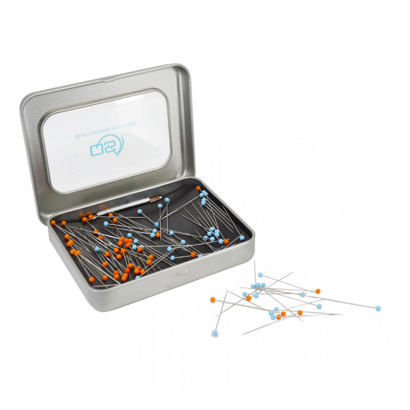 A metal tin filled with sewing pins, featuring orange and blue heads, with some pins scattered outside.