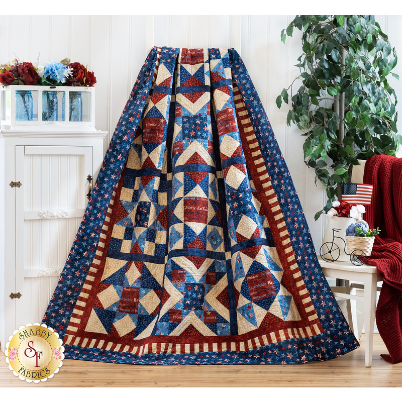 Stars and stripes quilt made of geometric blocks featuring red, blue, and cream, patriotic fabric prints.