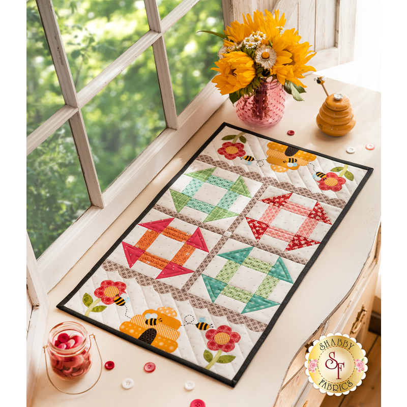 Table runner featuring geometric squares along with bee and floral appliqué on each end.