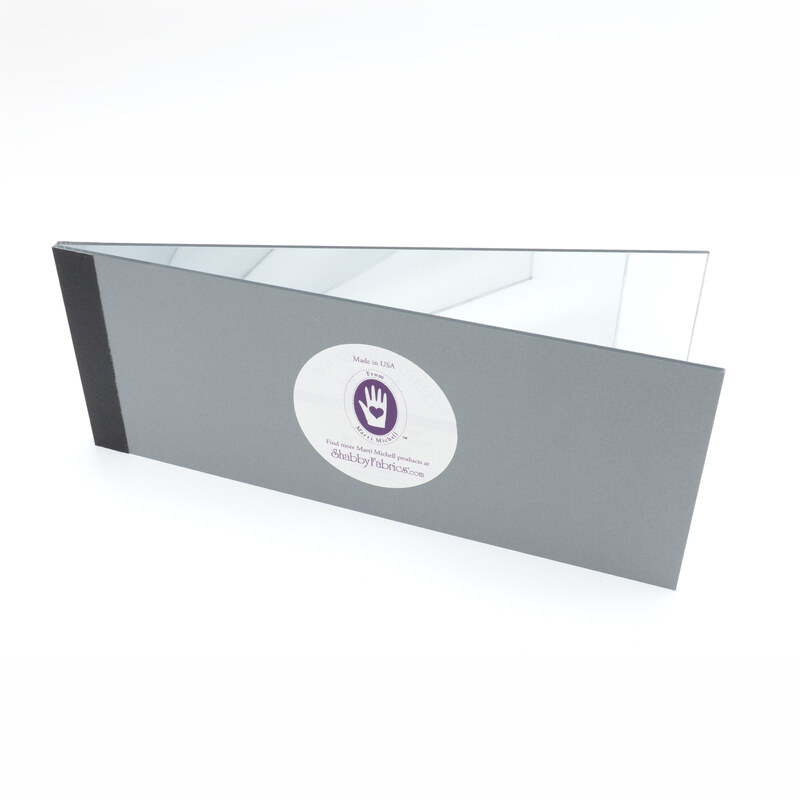 The gray Magic Mirror with a black spine, slightly opened and featuring the Marti Mitchell/Shabby Fabrics logo with a purple handprint.