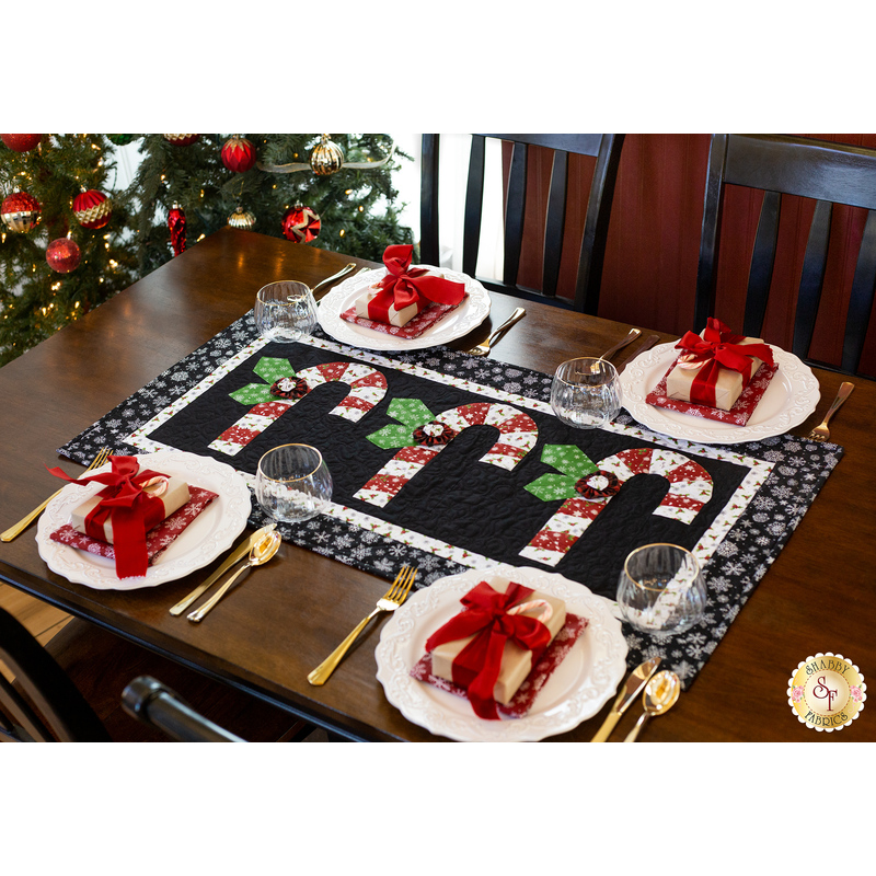 Black and white table runner featuring 3 candy canes with fabric yo-yos, all made of Winter themed fabric prints.