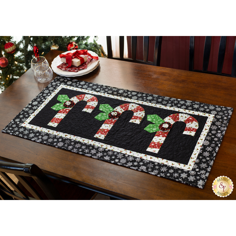 Black and white table runner featuring 3 candy canes with fabric yo-yos, all made of Winter themed fabric prints.