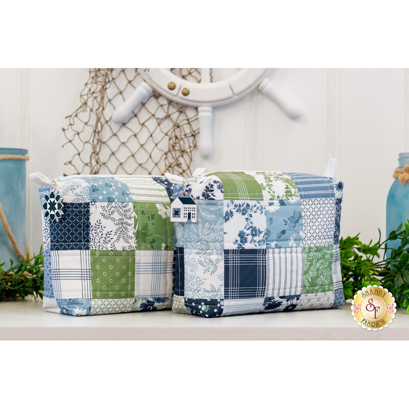 Two small bags with hanging charms and patchwork design made of blue, green, and white summer themed fabrics.
