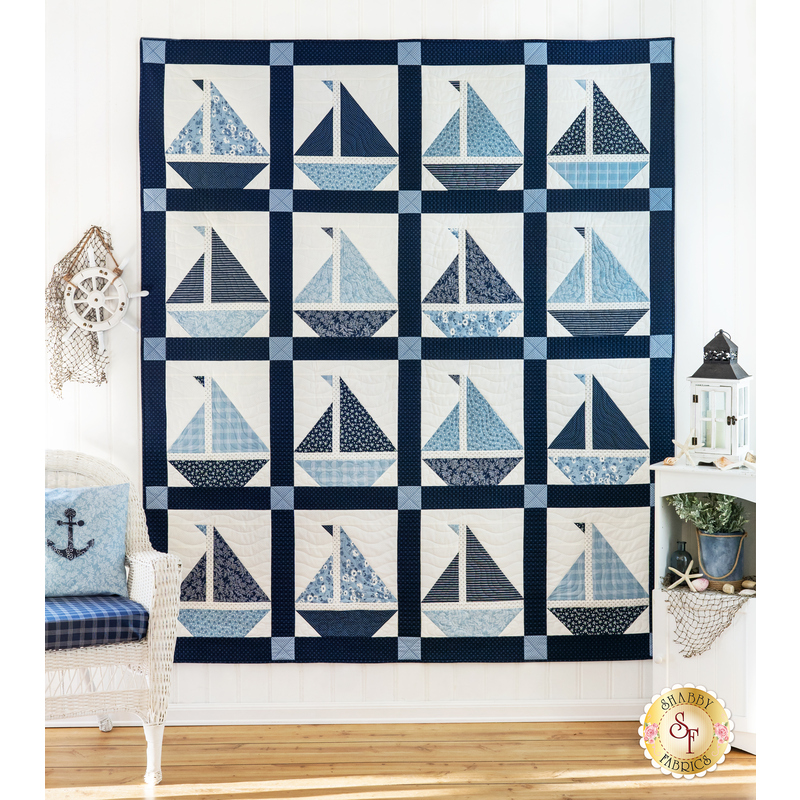 Quilt featuring blocks of geometric sail boats made of white and blue fabrics.