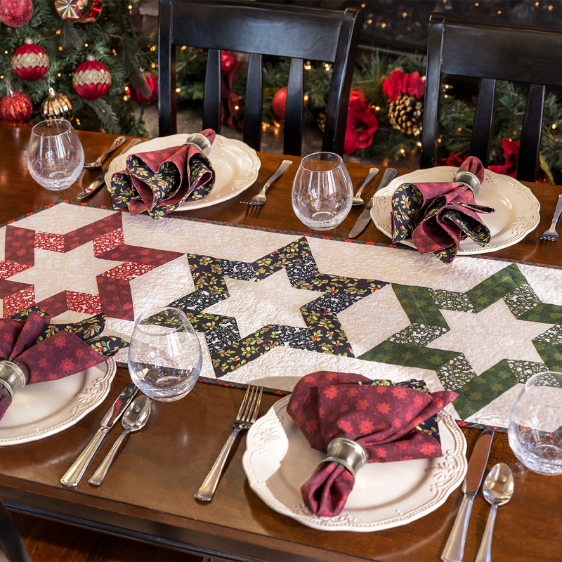 A festive dining table set with elegant plates, glasses, and star-patterned table runner, surrounded by holiday decor.