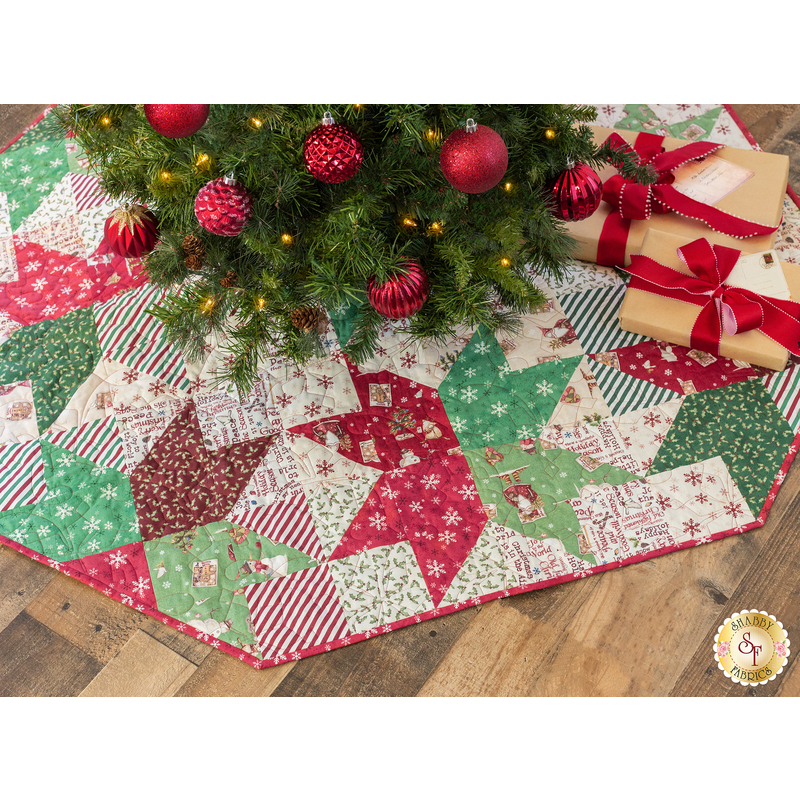 Tree skirt with patchwork and geometric star design made of red, white, and green, Christmas themed fabrics.