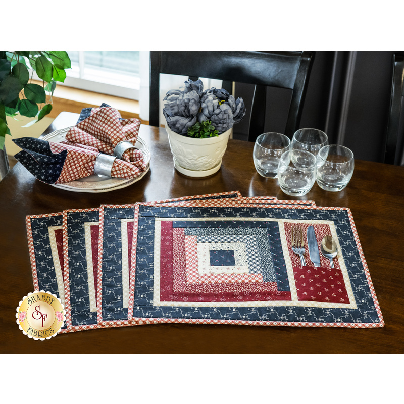 Placemats with log cabin rectangular strip design featuring a pocket for silverware and red, blue, and cream fabric prints.