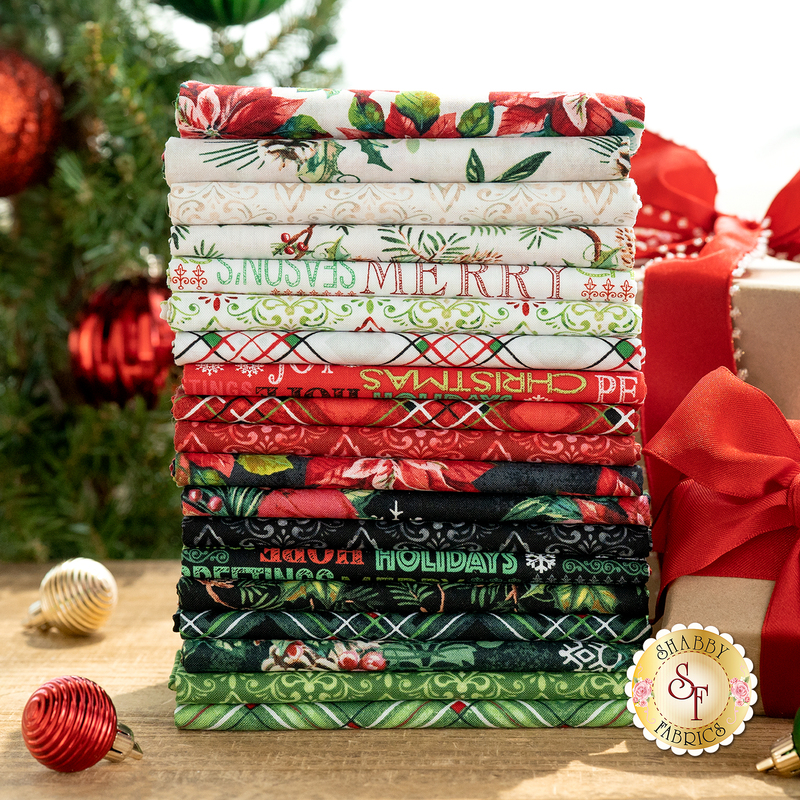 A stack of folded fabrics in festive colors and patterns, including reds, greens, and whites, arranged neatly. The fabrics feature Christmas-themed designs such as floral motifs and holiday greetings. In the background, there are holiday decorations, including ornaments and a gift with a ribbon.