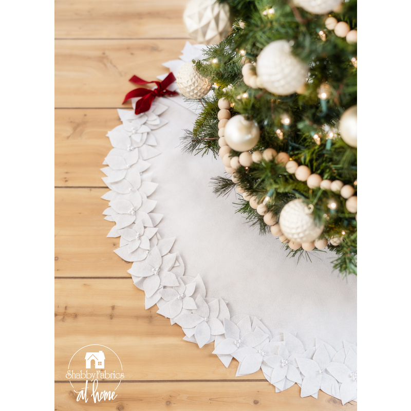 All white tree skirt with a border of layered fabric flowers and foliage.