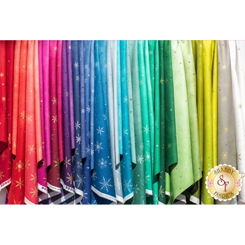 A variety of colorful fabrics draped vertically, featuring a gradient of shades from red and pink to blue, green, and yellow. Each fabric has a subtle pattern with small stars and a white border along the bottom.