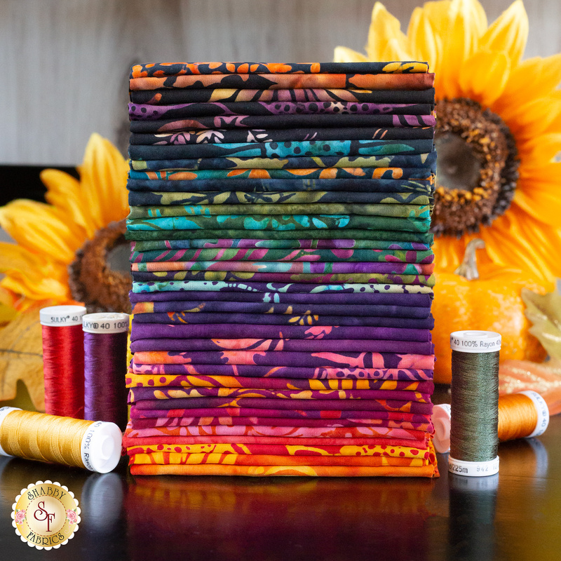 A stack of colorful batik fabrics included in the Bonfire Batiks One Yard Set