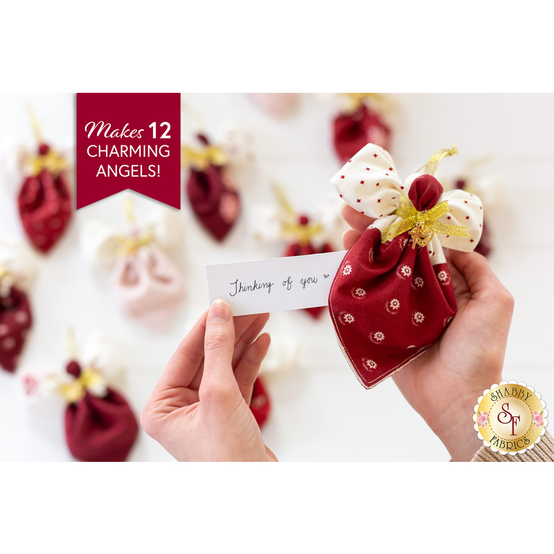 A hand holds a red and white fabric angel ornament while a note reading Thinking of you is displayed. In the background, multiple similar fabric angels are visible, featuring various colors and patterns. A banner at the top states, Makes 12 Charming Angels!